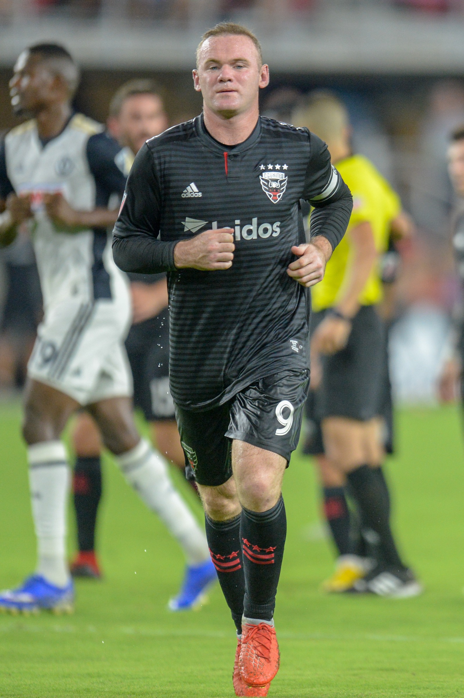 Wayne Rooney running in a black D.C. United kit with the captain's armband in 2018.