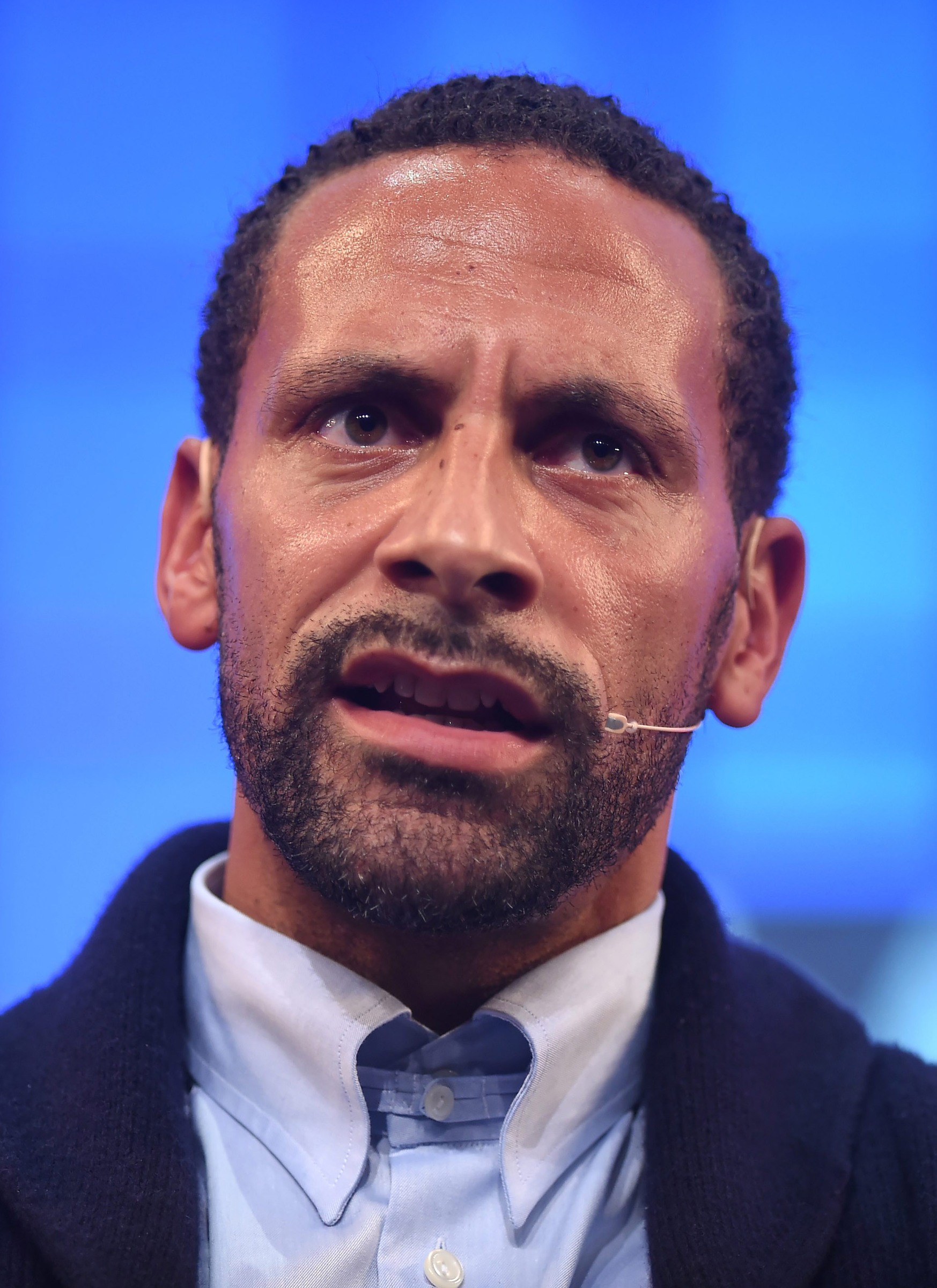 Close-up of Rio Ferdinand speaking on stage at Web Summit 2015 with a headset microphone.