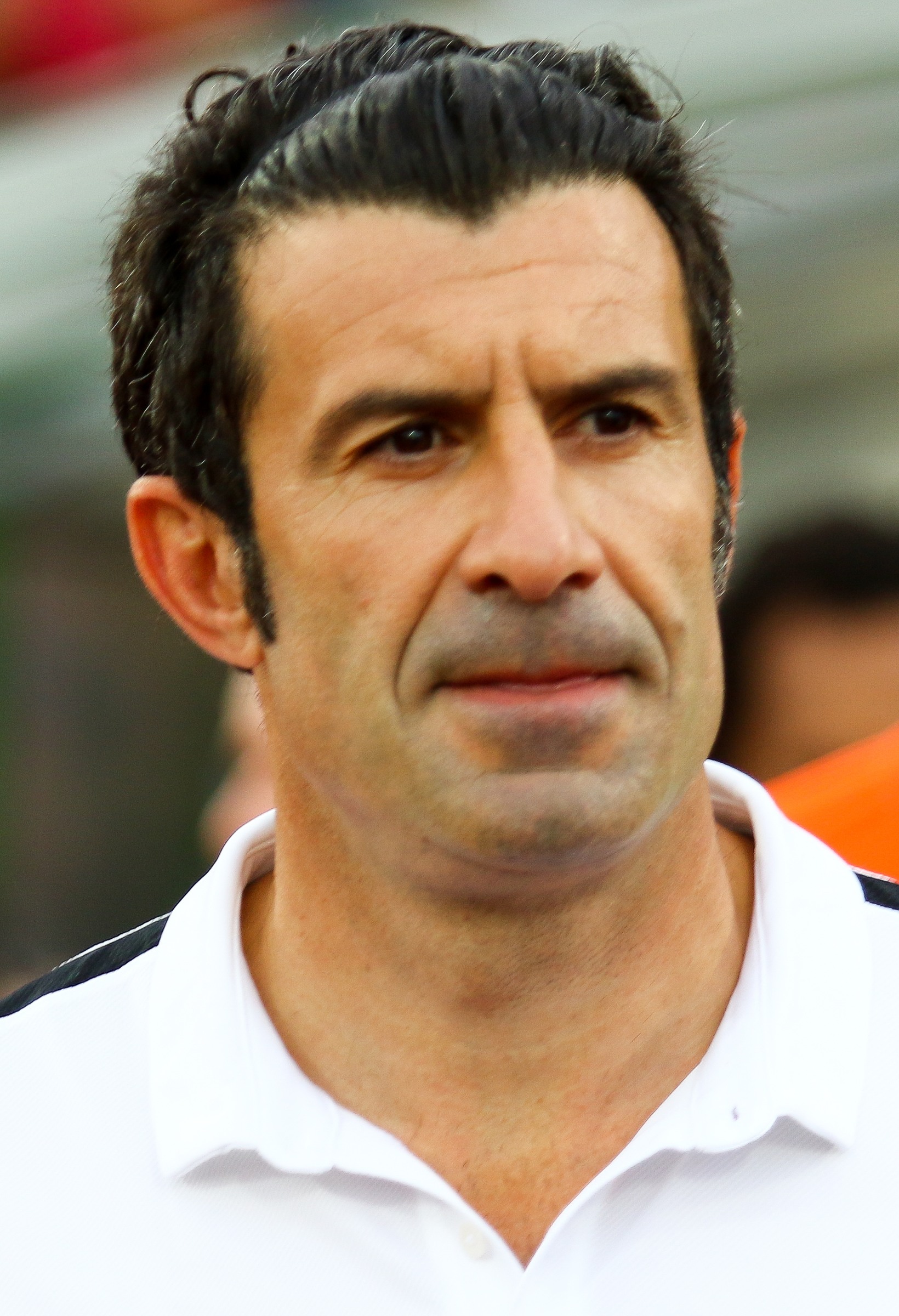 Close-up portrait of Luís Figo in a white collared shirt at a football event in 2017.