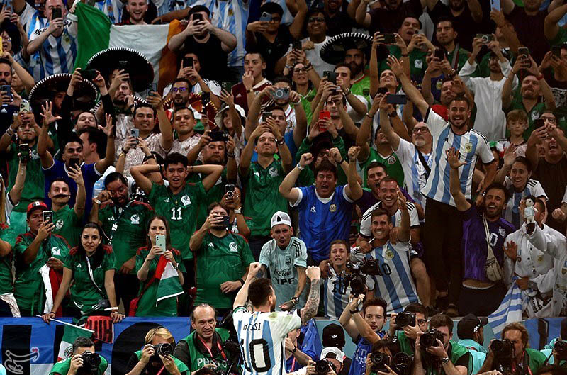 Messi raising his arms towards the stands, with his Argentina number 10 shirt visible.