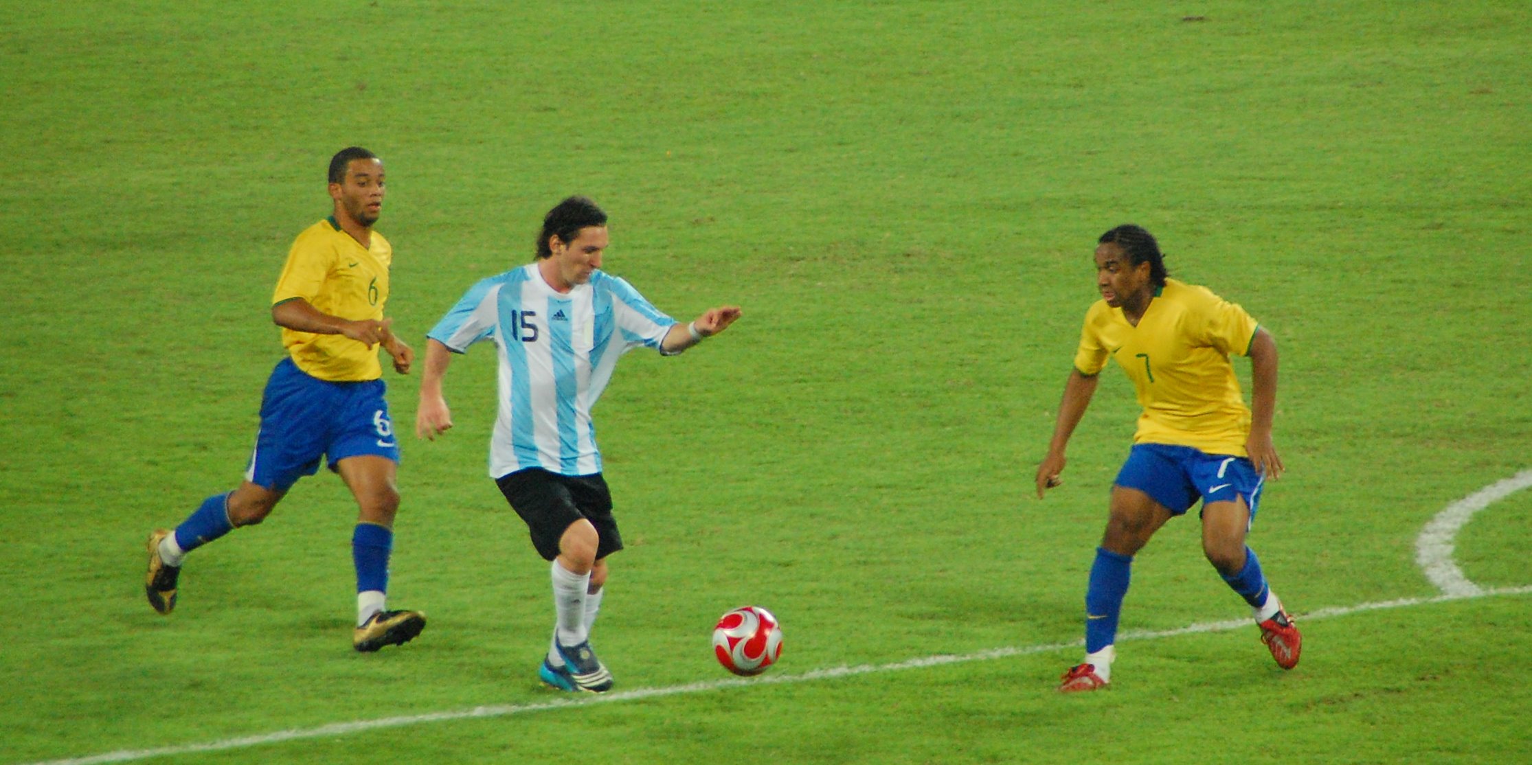 Messi in Argentina’s number 15 shirt carrying the ball between two Brazil players.